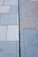 Cast iron rain or anover metal stormwater drainage system a downspout and slit tray with garbage on urban street paving walkway