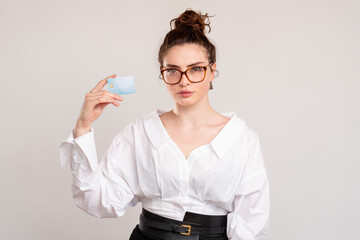 Business investment. Bank deposit. Confident woman in white shirt glasses holding credit card isolated on light copy space background. Financial management. Economy profit.