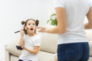 Fototapeta premium Photo of little brunette little girl trying to apply make up,