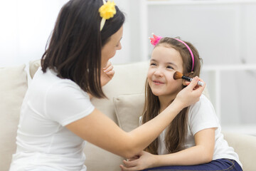 Photo of mother and daughter spending time at home together having fun putting make up on.