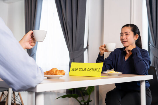 Asian Couple Sitting Separated In Restaurant Eating Food To Protect Infection From Coronavirus (covid-19), Social Distancing Rules In Practice After Lockdown, New Normal Concept