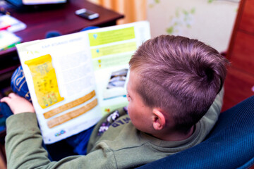 Top view Caucasian nine years old schoolboy reading a book, learning exercise books