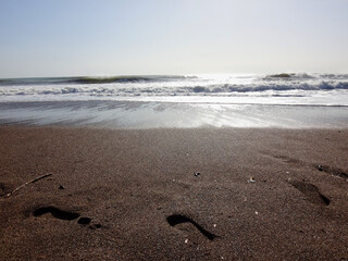 View from sand beach to water of sea and small waves in a nice day or evening with blues sky and bright sun. The concept of a holiday on the sea or ocean in the South.