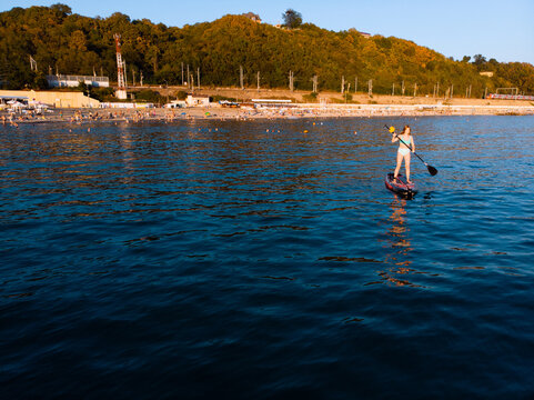 Attractive Woman on Stand Up Paddle Board, Woman paddling on sup board and enjoying turquoise transparent water. Tropical travel, wanderlust and water activity concept. Sunset and relax
