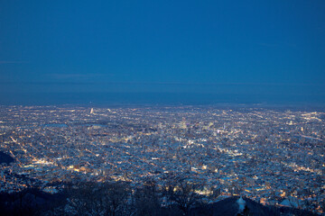 View from top of Mt. Moiwa in Sapporo city, Hokkaido, Japan during winter with night cityscape blur background.