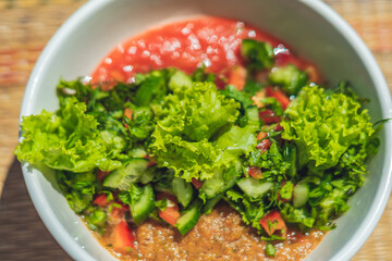 Raw vegan salad with green leaves mix vegetables in white bowl. Cooking recipe blended tomato...