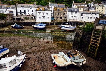 Boats in Polperro harbour during low tide on cloudy afternoon Cornwall, England, UK