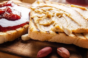 Low angle closeup view at peanut butter and jam sandwiches on cutting board. Healthy eating concept