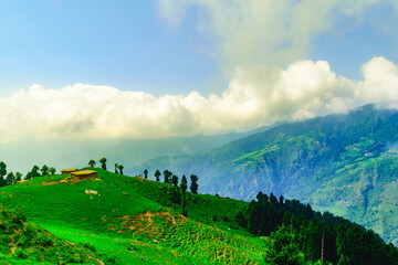 View of abandoned Hut made of stones & mud with cloudy blue sky background during sunset enroute to Prashar Lake trekking trail from Baggi village, Mandi, Kullu Manali region, Himachal Pradesh, India.