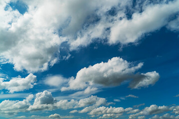 Picturesque white clouds illuminated by sunlight on a blue sky.