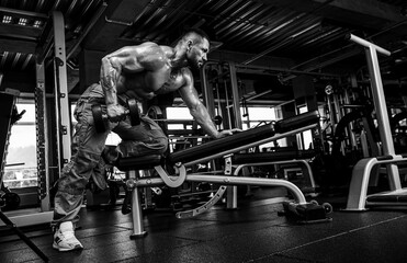 Attractive tall muscular bodybuilder doing heavy deadlifts in moder fitness center.