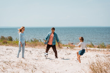 Selective focus of family playing football on beach