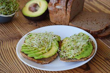 Sandwich of tender, juicy germinated alfalfa and avocado sprouts on slices of rye bread. This is a great idea for those who watch their health.healthy morning breakfast or snack