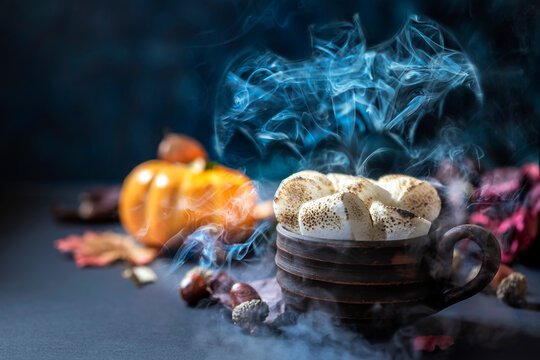A figurine of a bat paired with a cup of hot winter drink. Fairy tale concept on dark background.