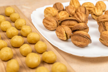 Small balls of cookie dough on a wooden Board and a plate of ready made cookies a Nut with boiled condensed milk. selective focus