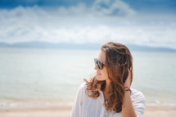 Fototapeta na wymiar Woman with curly hair in sunglasses on the beach. Sea travel