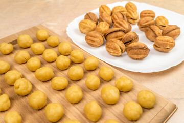 Small balls of cookie dough on a wooden Board and a plate of ready made cookies a Nut with boiled condensed milk. selective focus