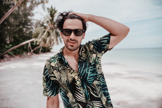 Portrait Of Sexy Latino Guy Brunet Man In Hawaiian Shirt And Sunglasses On Tropical Beach. Men's Fashion And Beauty In Travel And Vacation