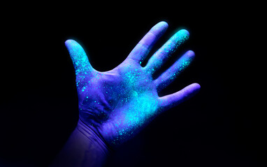 UV Ultraviolet light on a hand illustrating the effect of bacteria and viruses on a surface that...