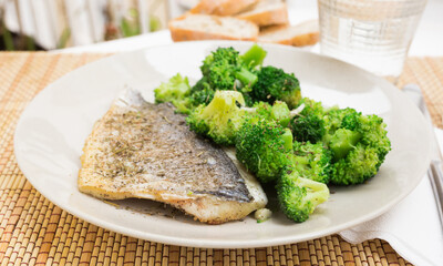 dish of fried dorado fish fillet with boiled broccoli