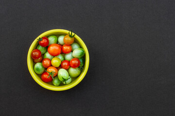 colorful cherry tomatoes on dark background with copy space