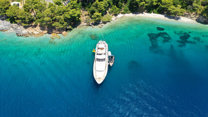 Aerial drone photo of yacht anchored in famous crystal clear bay and turquoise beach of Panormos, Skopelos island, Sporades, Greece