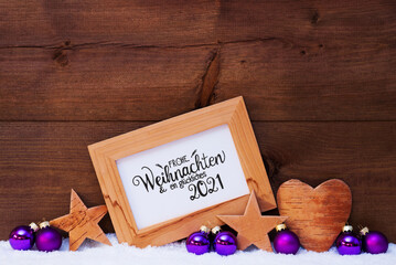 Frame With German Calligraphy Frohe Weihnachten Und Ein Glueckliches 2021 Mean Merry Christmas And A Happy 2021. Purple Christmas Decoration Like Ball, Star And Heart. Wooden Background With Snow
