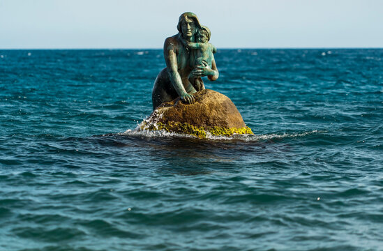 Sculpture of a mermaid with a child in her arms, in the sea on a rock. Mishor, Crimea.