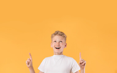 Smiling boy pointing finger up at copy space