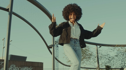 black woman with 70s disco style look dancing funk disco dance outdoors Huge afro hairstyle Black woman have fun and dancing