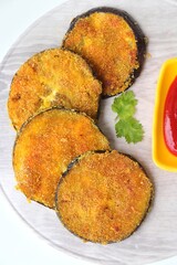 Indian side dish or appetizer  Vangyache Kaap, fried Eggplants, Crispy brinjal fry, Aubergine disks, served with tomato ketchup. With copy space