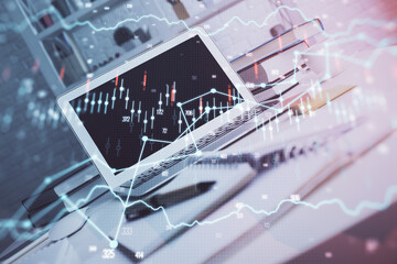 Stock market graph on background with desk and personal computer. Double exposure. Concept of financial analysis.