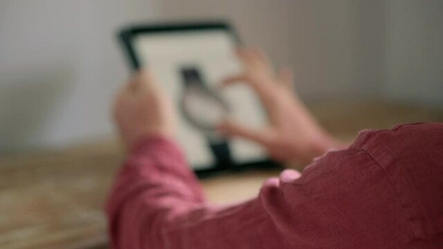 man is viewing product catalog on internet site of store, using tablet
