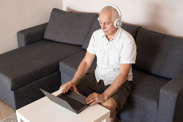 Smiling senior man using laptop, typing on keyboard, online education, business