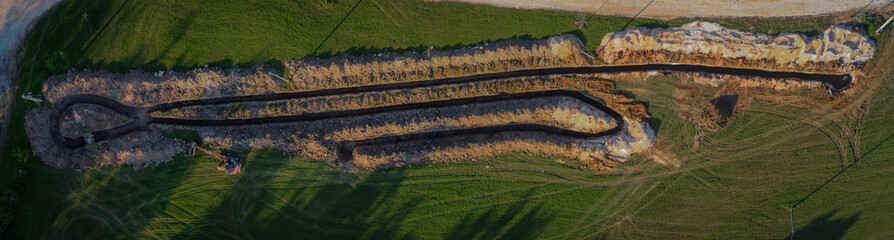 Aerial drone view of geothermal heating collector pit or trench in the ground. Excavation of ditch...