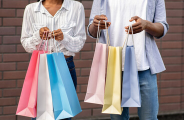 Black Friday. African american guy and girl with colored shopping bags