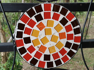 The backrest of the chair is decorated with mosaic decorated in warm colors of red, orange and...