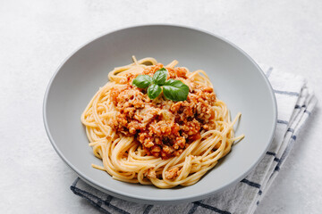 Italian spaghetti pasta with bolognese meat sauce on a light concrete, stone background