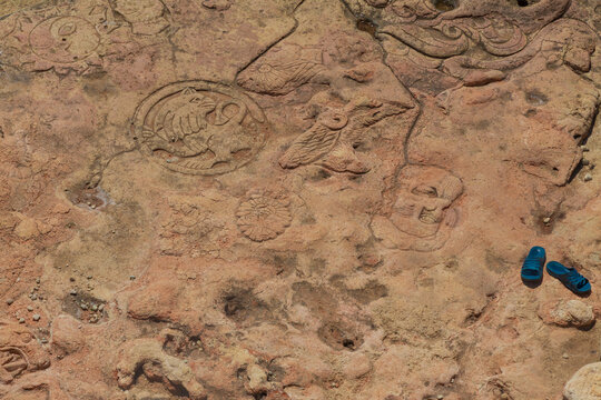 The background image is a fragment of a rock decorated with various drawings. There are rubber slippers on the side of the rock