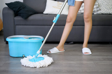 Happy young Woman Cleaning Floor With Mop In living room
