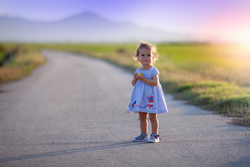 Niña de un año con vestido azul en un camino solitario