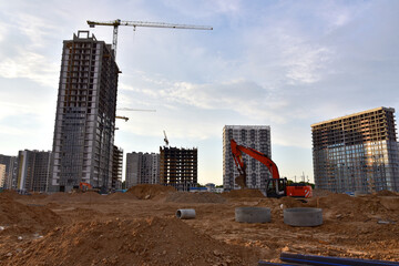 Excavator on earthmoving at construction site. Road work and Dig pit foundation. Tower cranes in...