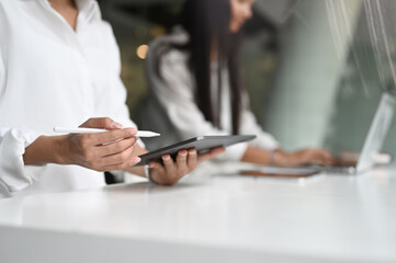 Cropped image businesswoman working on digital tablet using stylus pen on white table.