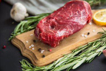 Fototapeta na wymiar Raw beef steak on a cutting board with spices. Creative atmospheric decoration.