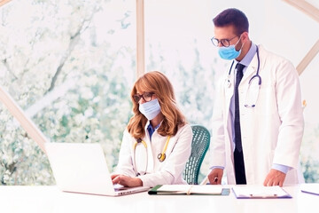 Healthcare workers wearing face masks while working together in hospital