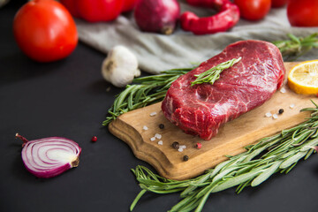 Raw beef steak on a cutting board with spices. Creative atmospheric decoration.