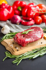 Raw beef steak on a cutting board with spices. Creative atmospheric decoration.