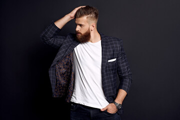 Portrait of confident man with red beard corrects his hair