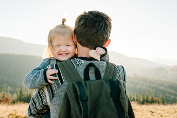 The daughter hug father on nature. Dad with backpack and child walk in the autumn. Family spending time together in mountain on vacation. Holiday trip concept. World Tourism Day. back view.