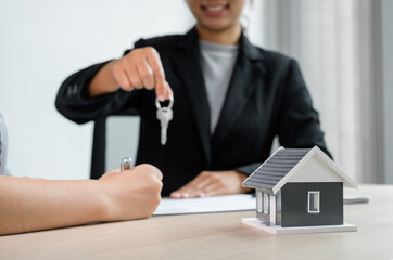 Real estate agent broker hand over the house key to the new owner after completing the signing according to agreement renting a house and buy house insurance Home insurance concept